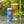 Load image into Gallery viewer, A can of Little Ox Brewery Shell Yeah beer next to a filled glass of the golden beer, set on a reflective table with a blurred garden background.
